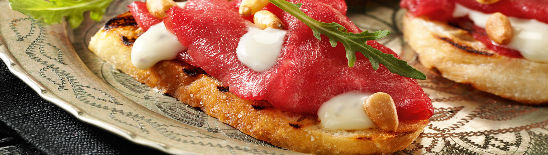 Crostini mit Carpaccio, Rucola und Pinienkernen