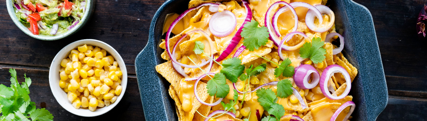 Nachos com queijo, cebola roxa, milho, guacamole e coentros