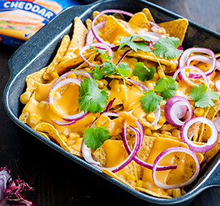 Nachos com queijo, cebola roxa, milho, guacamole e coentros