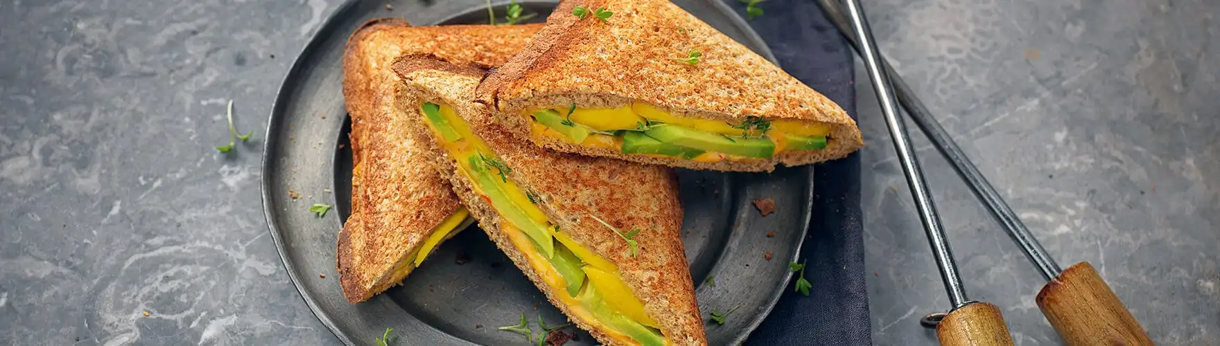 Tosti met cheddar, avocado, mango, tuinkers en sambal