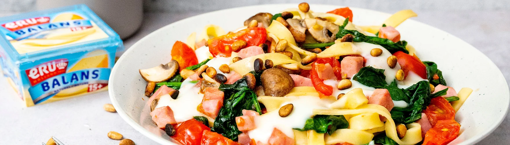 Verse tagliatelle met hamblokjes, spinazie, champignons, trostomaten en pijnboompitten