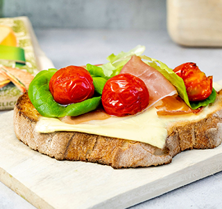 Geroosterd brood met biologische plakken kaas, parmaham, cherrytomaten en botersla