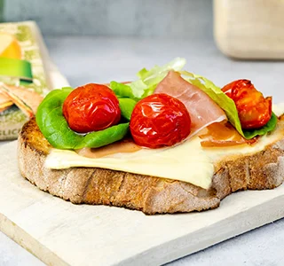 Geroosterd brood met biologische plakken kaas, parmaham, cherrytomaten en botersla