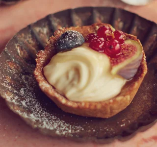 Granola taartjes met een mengsel van geitenkaas, vers fruit en honing