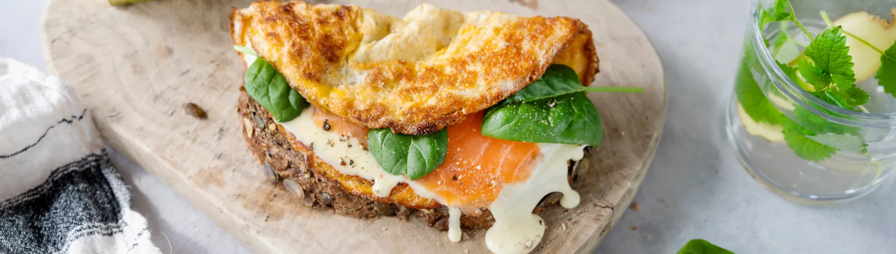 Boeren boterham belegd met een omelet, biologische kaas, zalm en babyspinazie