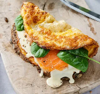 Boeren boterham belegd met een omelet, biologische kaas, zalm en babyspinazie