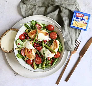 Maaltijdsalade met verschillende groenten, krokante kip, granaatappelpitjes en een dressing van belegen magere kaas met limoenrasp