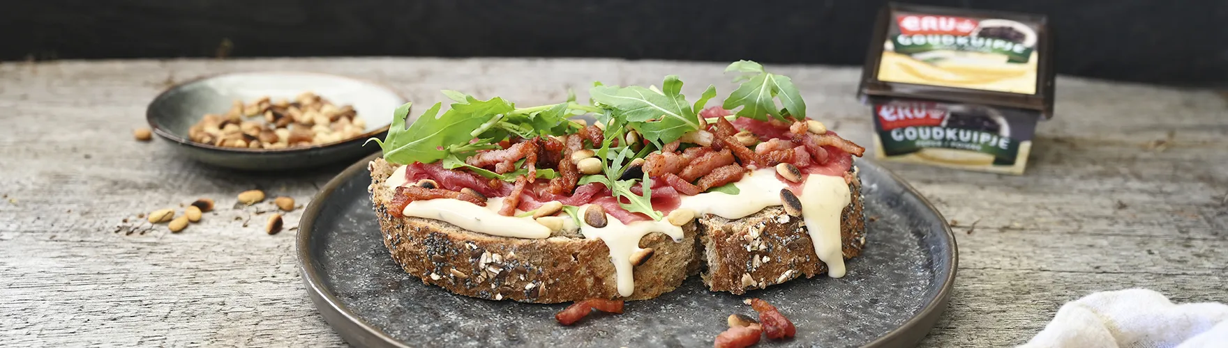 Landbrood met carpaccio, spekjes, rucola, pijnboompitten en kaas