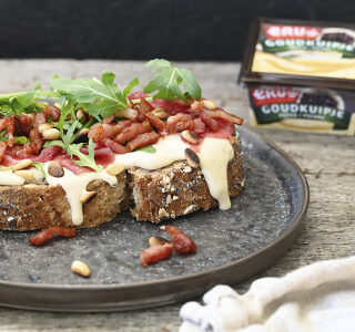 Landbrood met carpaccio, spekjes, rucola, pijnboompitten en kaas