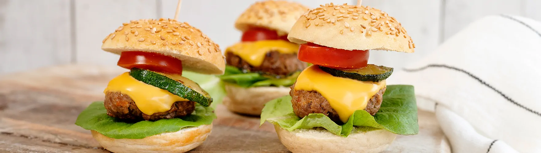 Mini hamburgers met plakjes cheddar, sla, cherrytomaten en gegrilde courgette