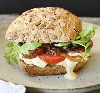 Pompoenbroodje met komijnekaas, tomaat, gekarameliseerde ui en rucola