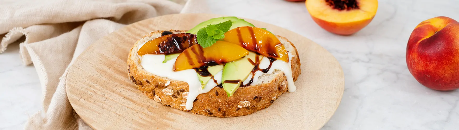 Geroosterd meergranenbrood met magere smeerkaas, avocado, warme nectarine en balsamicocrème